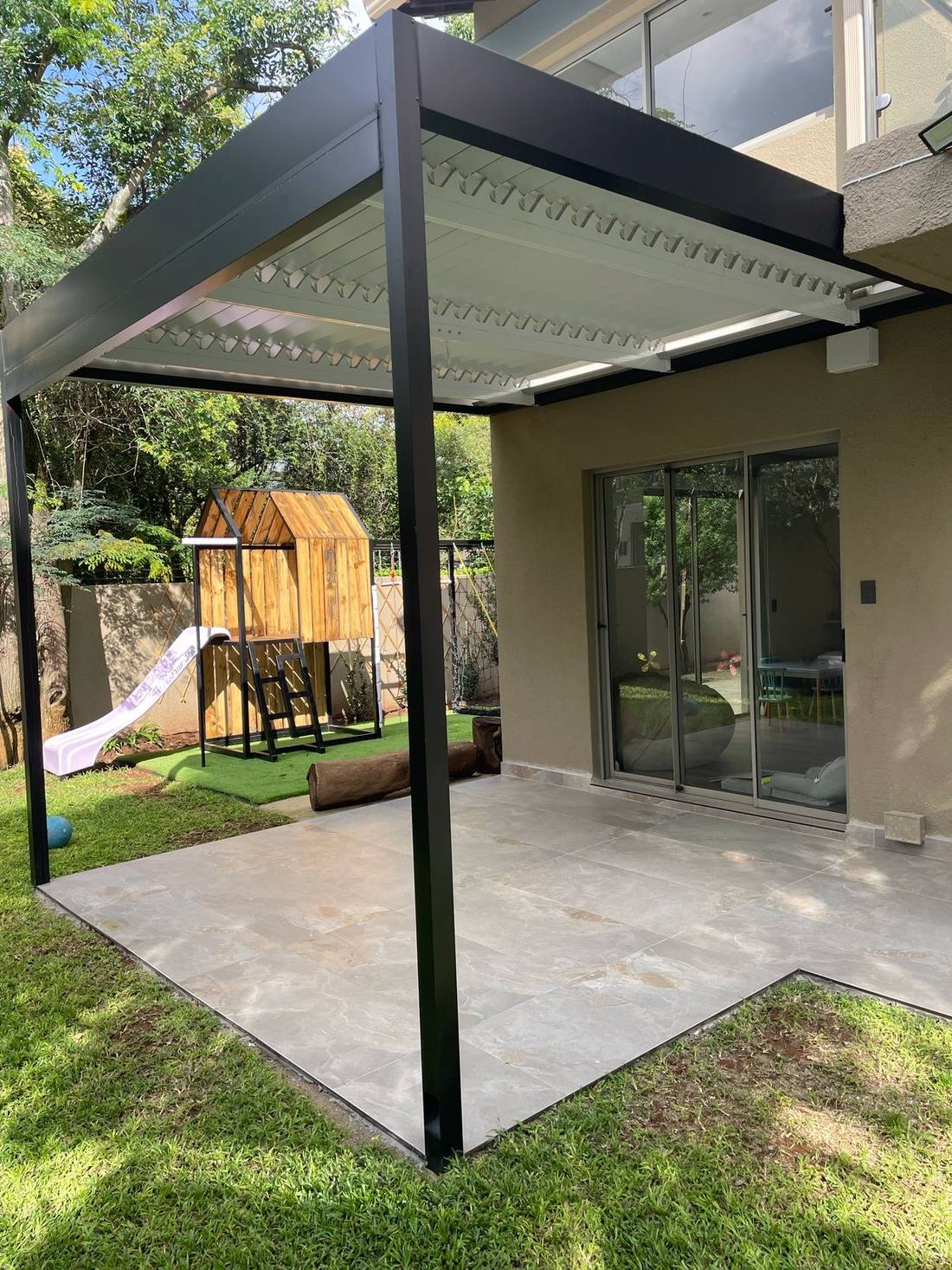 The Abbotsford patio louvre seen towards the play area and artificial lawn