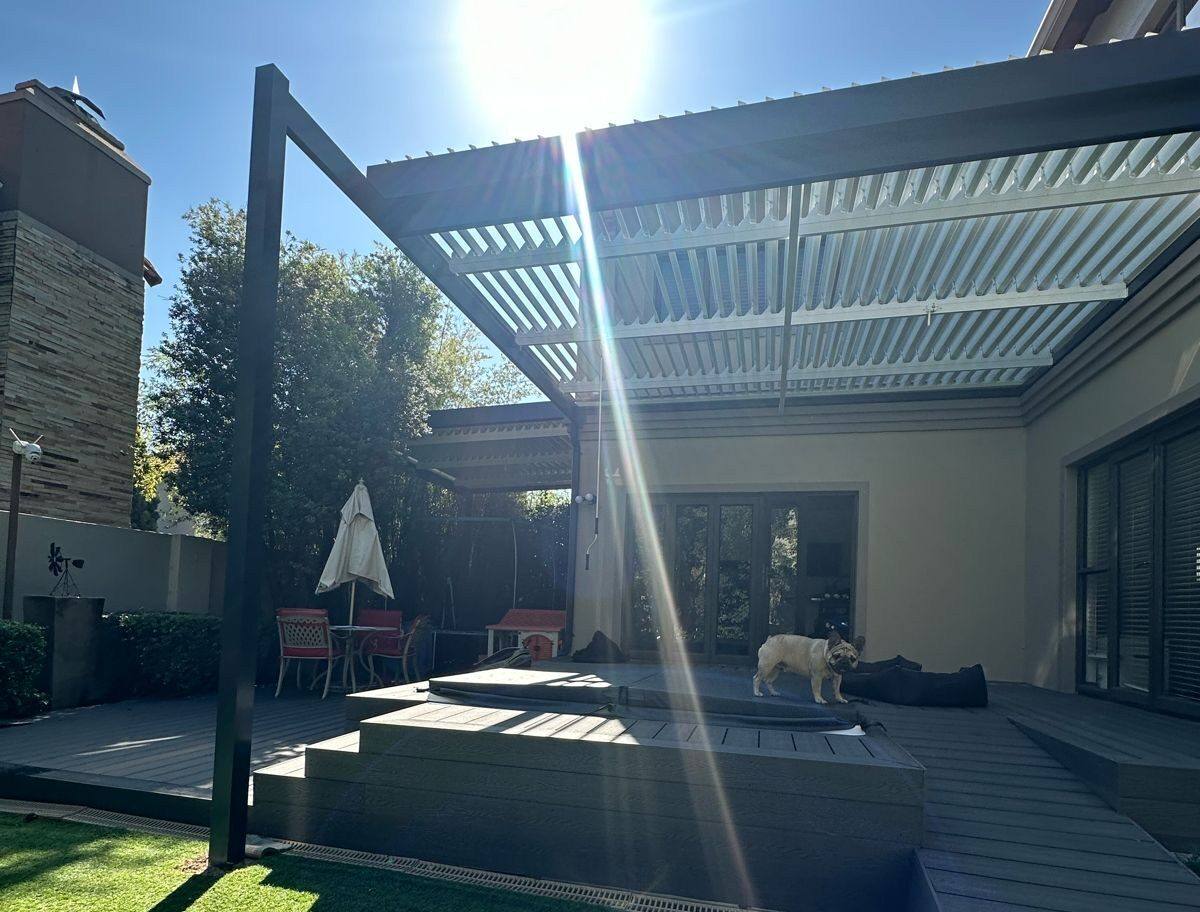 Charcoal aluminium louvred pergola on slim posts over a raised composite deck